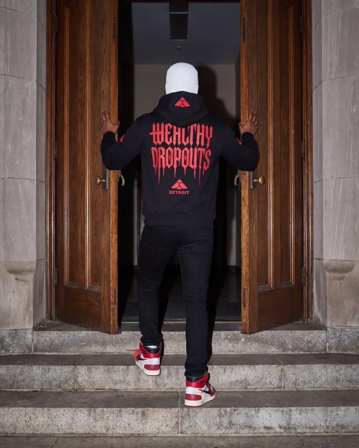 Tuition in black with red lettering, worn from behind: pushing open the oak doors of an old hall
