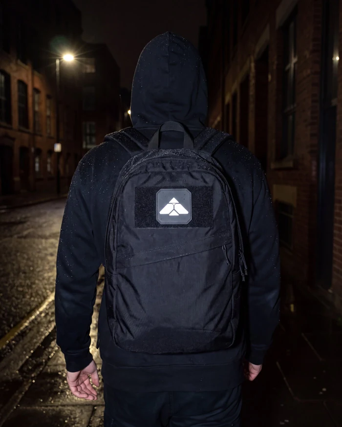 The Mark worn on a black backpack at night